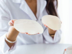 Doctor presenting silicone breast implants, comparing augmentation options