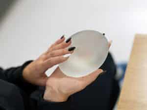 Hands holding a silicone breast implant, highlighting options for natural-looking breast augmentation results.